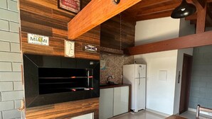 A modern kitchen with wooden accents, a black countertop, and a white refrigerator. - Pousada Rosa Paradise (Imbituba)