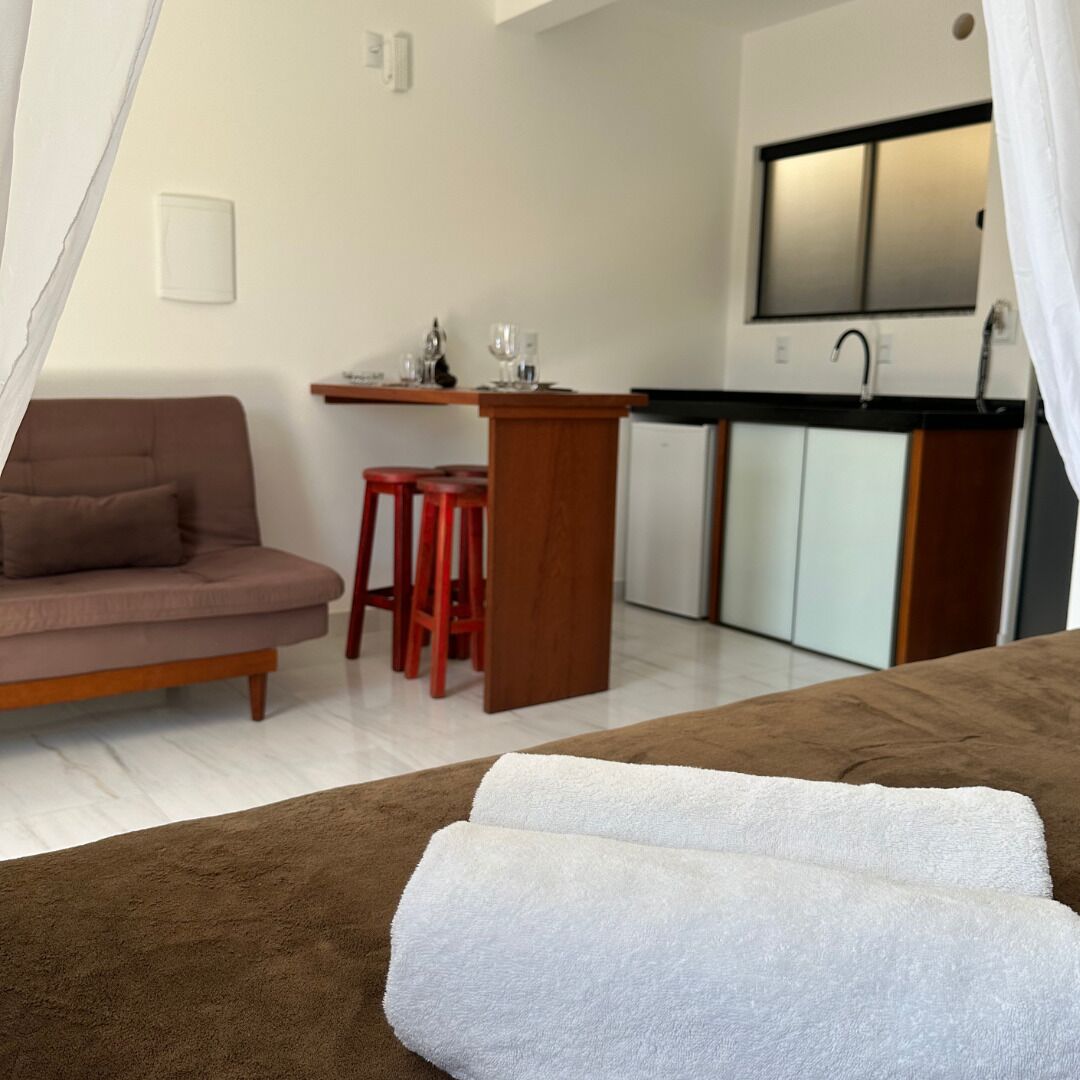 Ein kompakter Wohnraum mit Sofa, einer kleinen Küchenzeile und einem Bett mit weißen Handtüchern.