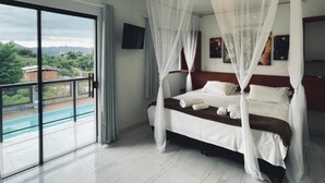 A bedroom with a bed, a TV, and a view of a swimming pool. - Pousada Rosa Paradise (Imbituba)