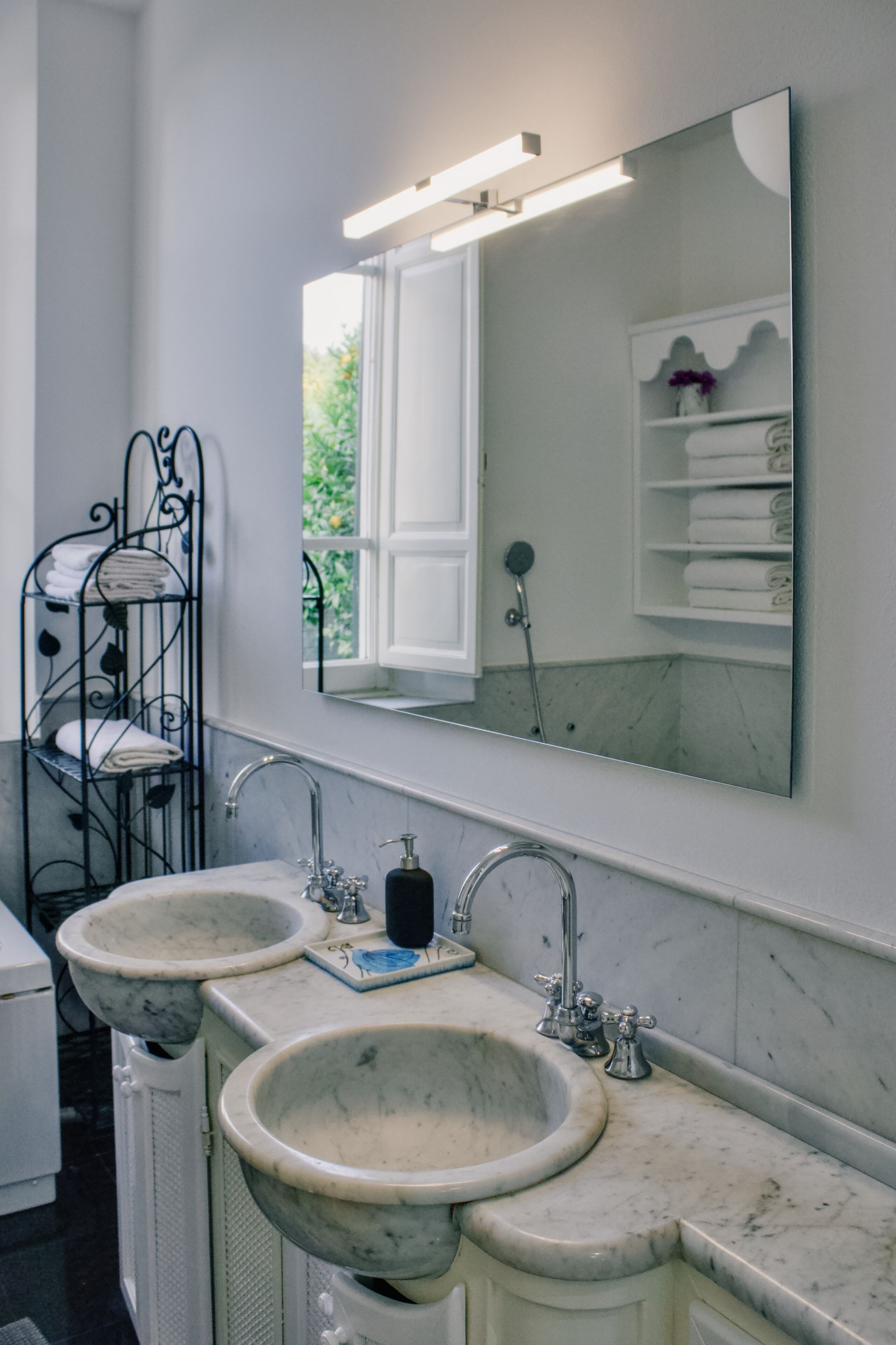 Une salle de bain avec deux lavabos, un miroir et une fenêtre.