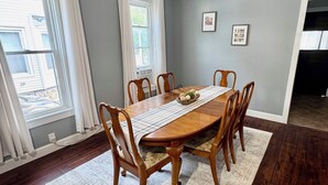 A dining room with a wooden table, chairs, a ceiling fan, and a view of the outside. - Geneva Getaway for Wine, Weddings & Lake Days (Geneva)
