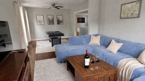 A living room with a sectional sofa, a wooden coffee table, a ceiling fan, and a television. - Geneva Getaway for Wine, Weddings & Lake Days (Geneva)