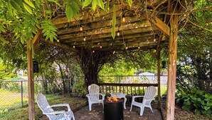 A covered outdoor seating area with white chairs and a central fire feature. - Geneva Getaway for Wine, Weddings & Lake Days (Geneva)