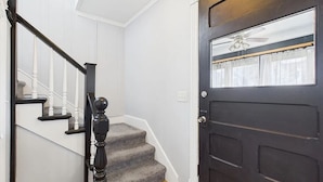 A staircase with white railings and a dark wooden door with a window and a ceiling fan. - Geneva Getaway for Wine, Weddings & Lake Days (Geneva)