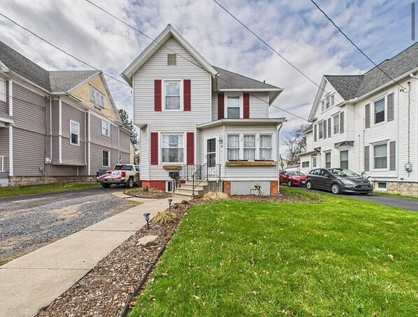 A two-story residential building with a front porch and a small front yard.