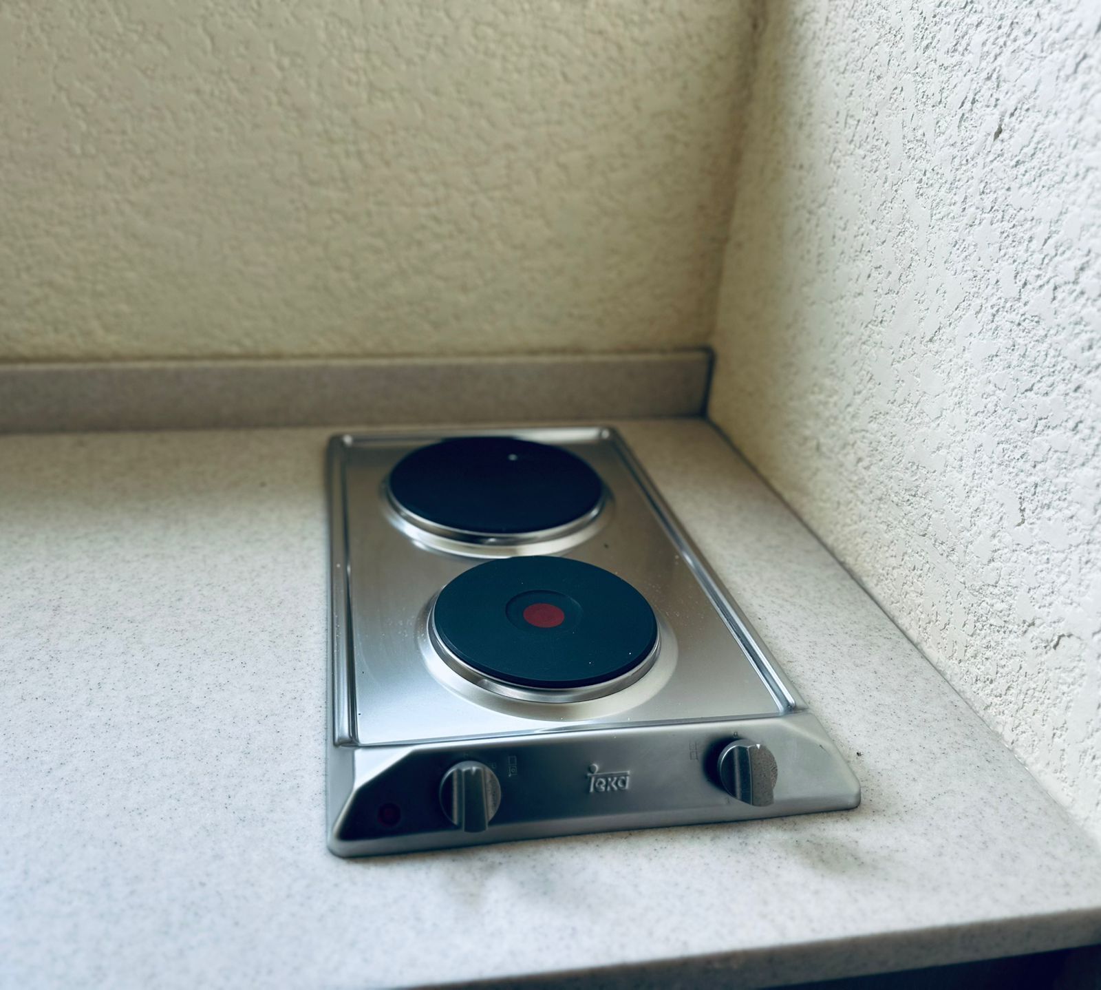 A compact, stainless steel electric stove with two burners and a control knob.