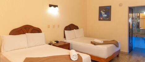 A hotel room with two beds, a nightstand, a painting, and a bathroom visible through an open door.