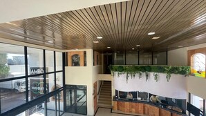 Un moderno vestíbulo de hotel con fachada de vidrio, una recepción, una escalera y una zona de estar.