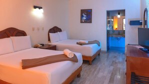 Habitación de hotel con dos camas, un escritorio, un televisor y un baño visible a través de una puerta abierta.