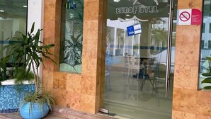 Entrada de un hotel con puerta de vidrio, un letrero que dice Euro Hotel y un cartel de prohibido fumar.
