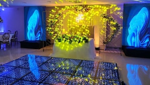 Un interior moderno con un arreglo floral central, una pantalla de proyección y un piso estampado.