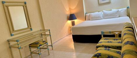Una habitación de hotel con una cama, un escritorio, una silla y un sofá.