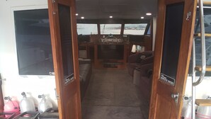 Interior de un barco con una puerta de madera que da a una sala de control y una zona de estar.