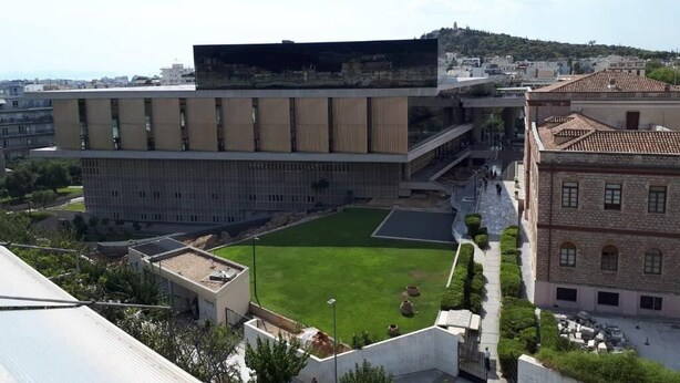 A modern building with a flat roof, a central courtyard, and a view of the surrounding cityscape. - Check Point - Acropolis Temple (Athens)