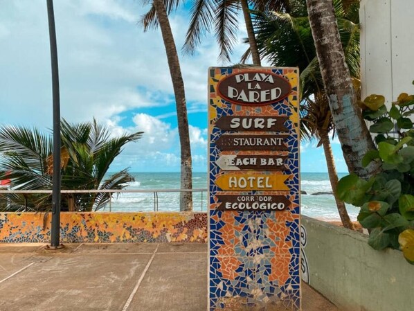 A sign with multiple directions for Playa La Dared, including surf, restaurant, beach bar, hotel, and a corridor named Ecologic.