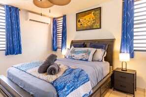 A hotel room with a bed, a nightstand, a lamp, and a painting on the wall.