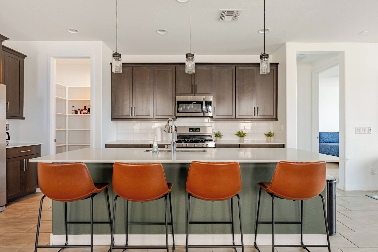 A modern kitchen with a central island, bar stools, and pendant lighting.