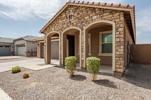 A residential building with a stone facade, multiple garage doors, and a gravel driveway. - Luxurious Arizona Retreat (Queen Creek)