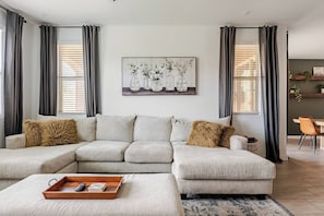 A living room with a sectional sofa, a coffee table, and a painting on the wall.