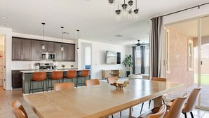 A modern kitchen with a dining area, a large wooden table, and a ceiling fan. - Luxurious Arizona Retreat (Queen Creek)