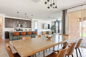 A modern kitchen with a dining area, a large wooden table, and a ceiling fan. - Luxurious Arizona Retreat (Queen Creek)