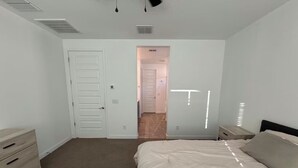 Une chambre à coucher comprenant un lit, une commode, une table de chevet et une porte donnant sur une autre pièce.