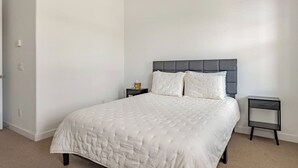 A bedroom with a bed, two bedside tables, and a door. - Luxurious Arizona Retreat (Queen Creek)