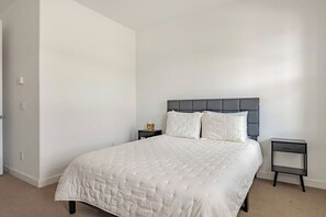 A bedroom with a bed, two bedside tables, and a door. - Luxurious Arizona Retreat (Queen Creek)