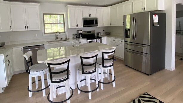A modern kitchen with white cabinets, stainless steel appliances, and a central island with bar stools.