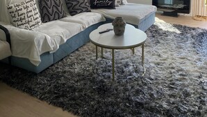 A living room with a sectional sofa, a round coffee table, and a ceiling fan.