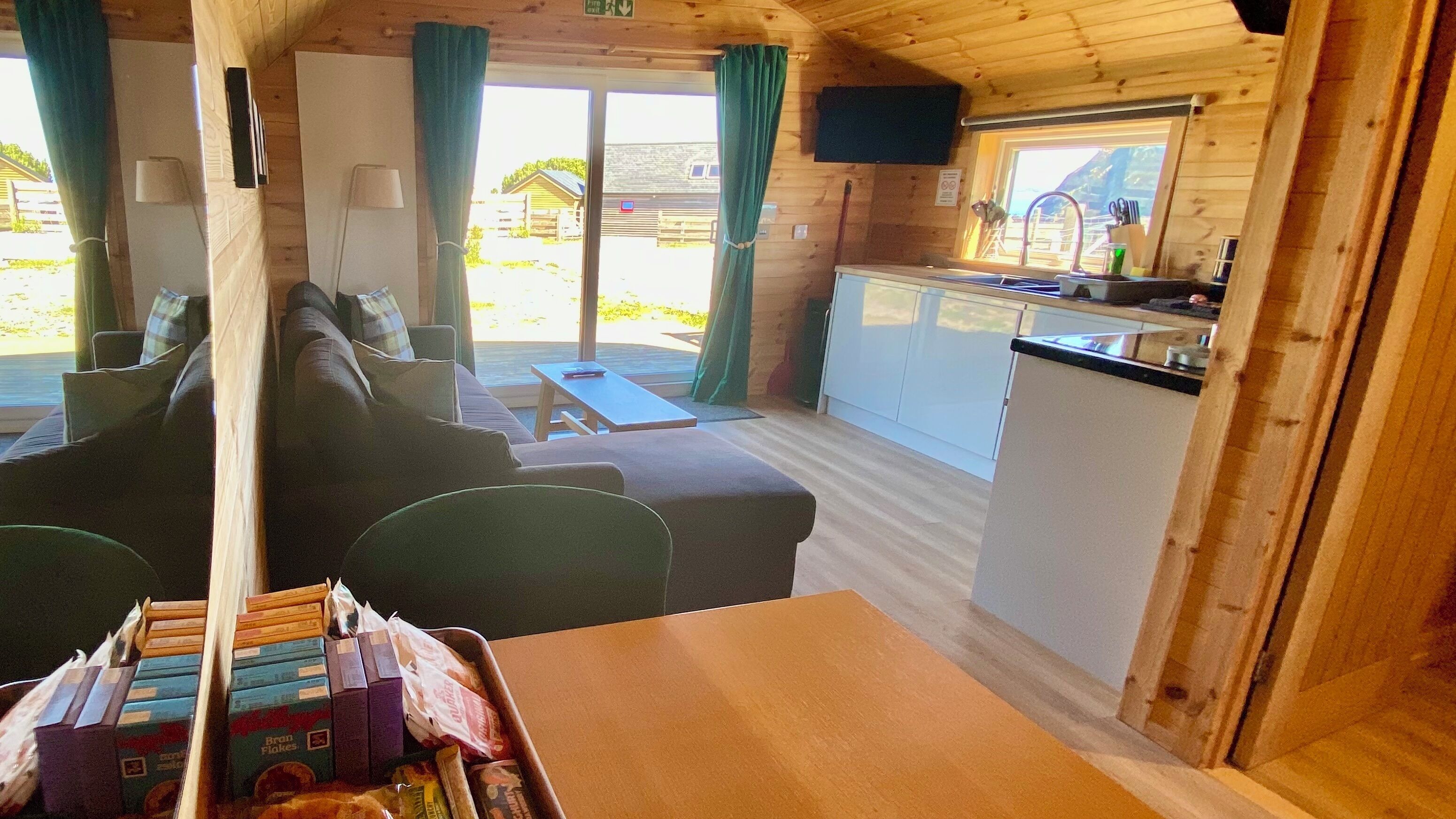 A cabin interior with a living area, kitchenette, and a dining table with breakfast items.