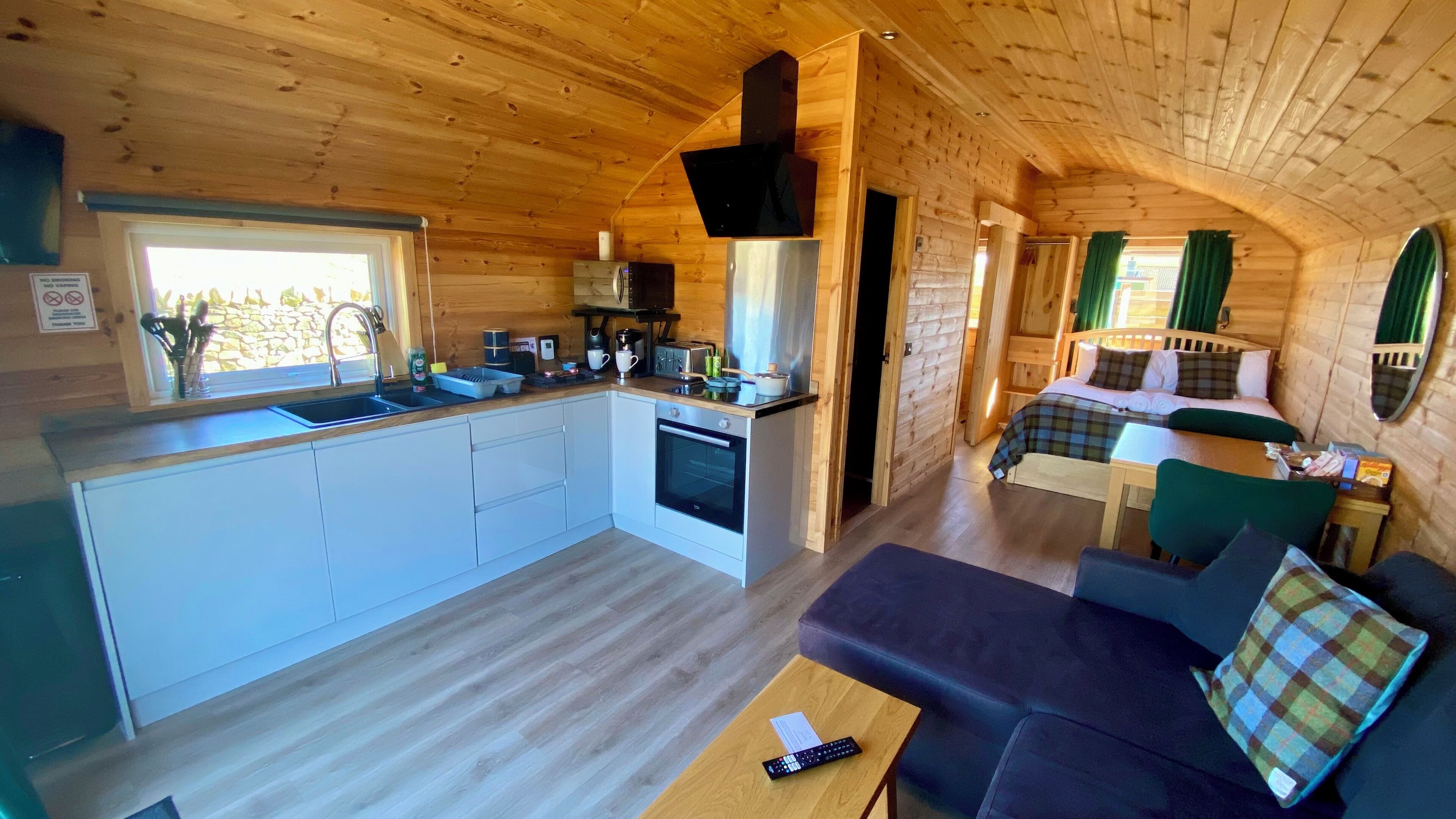 A compact cabin with a kitchenette, a sofa, and a bed.