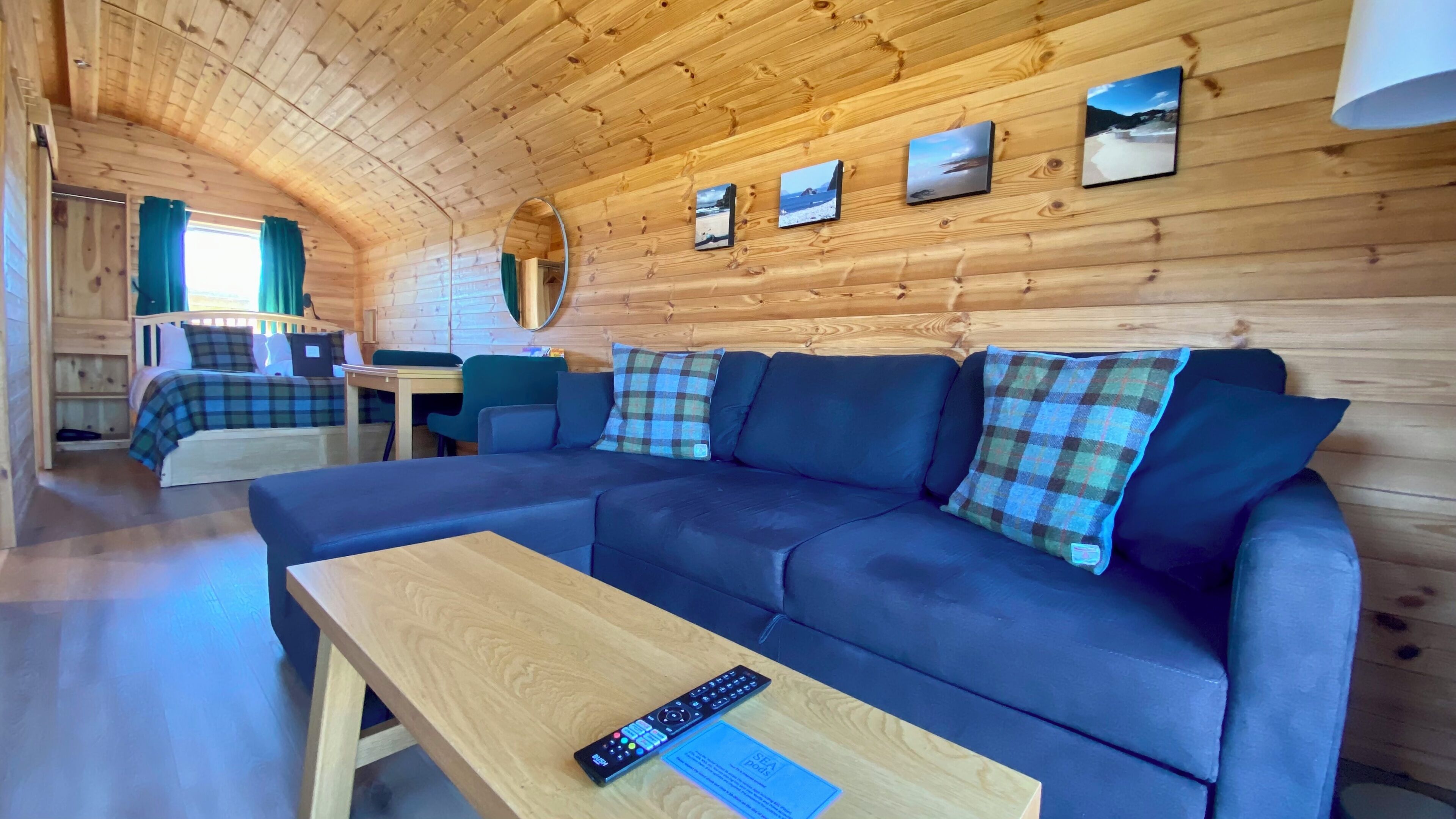 L’intérieur d’un chalet accueillant, avec un canapé, une table, un miroir et un lit.