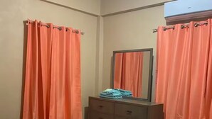Una camera da letto con un letto, una cassettiera e tende arancioni.