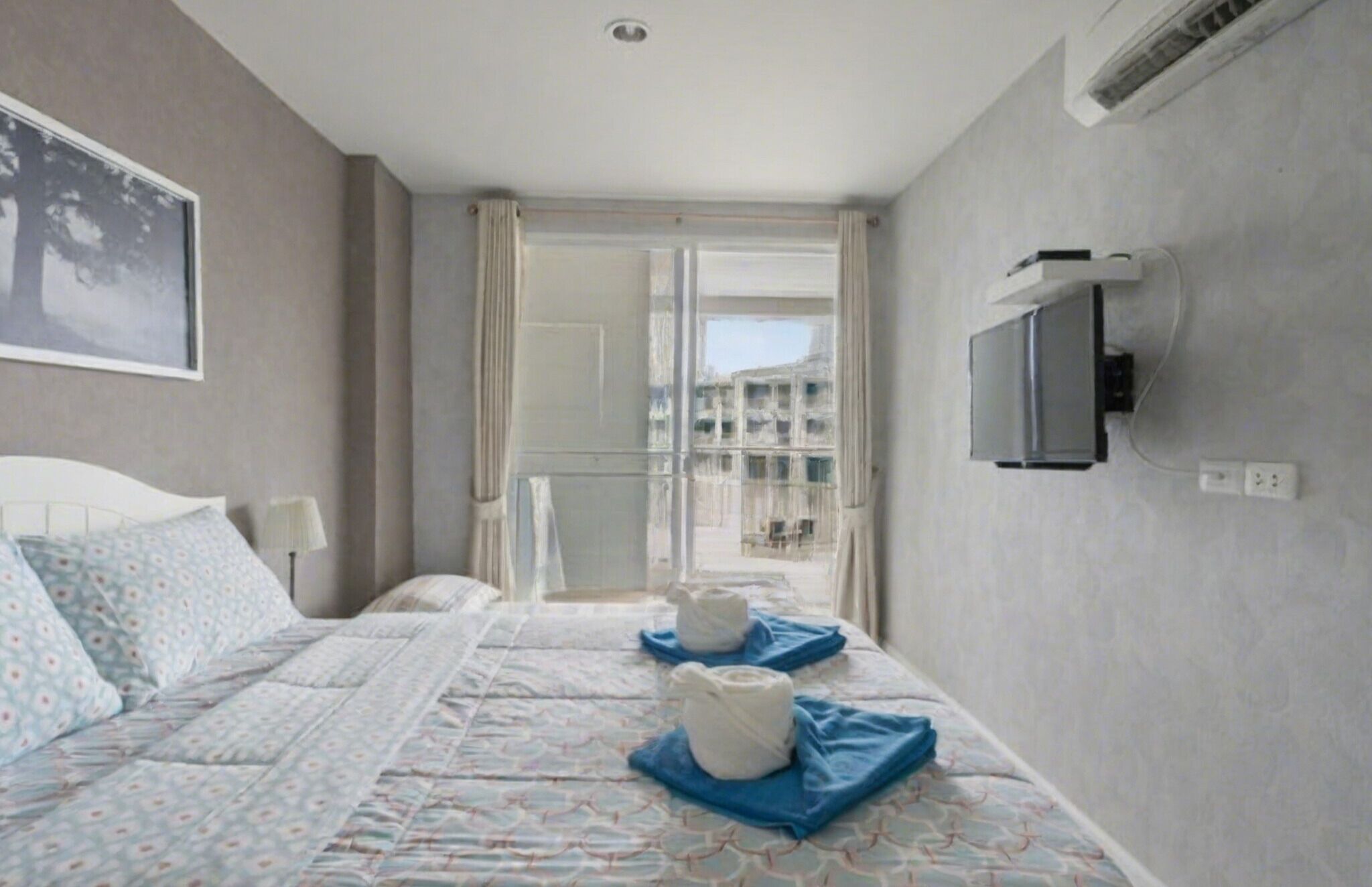 Une chambre d’hôtel avec un lit, une télévision et une vue sur un immeuble par la fenêtre.