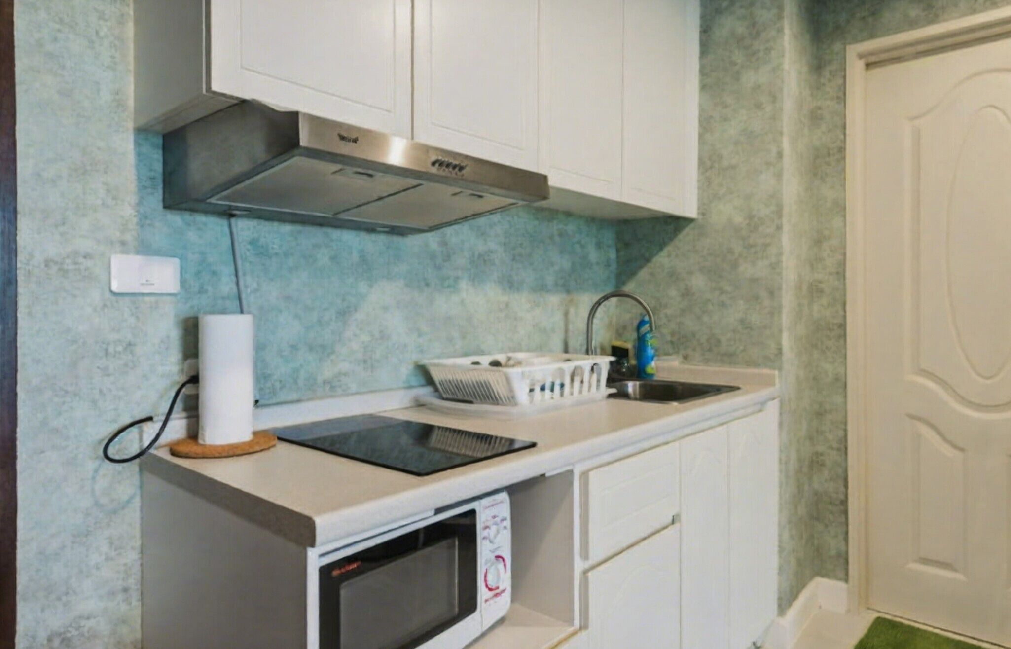 A compact kitchen with a built-in microwave, a kettle, and a sink.
