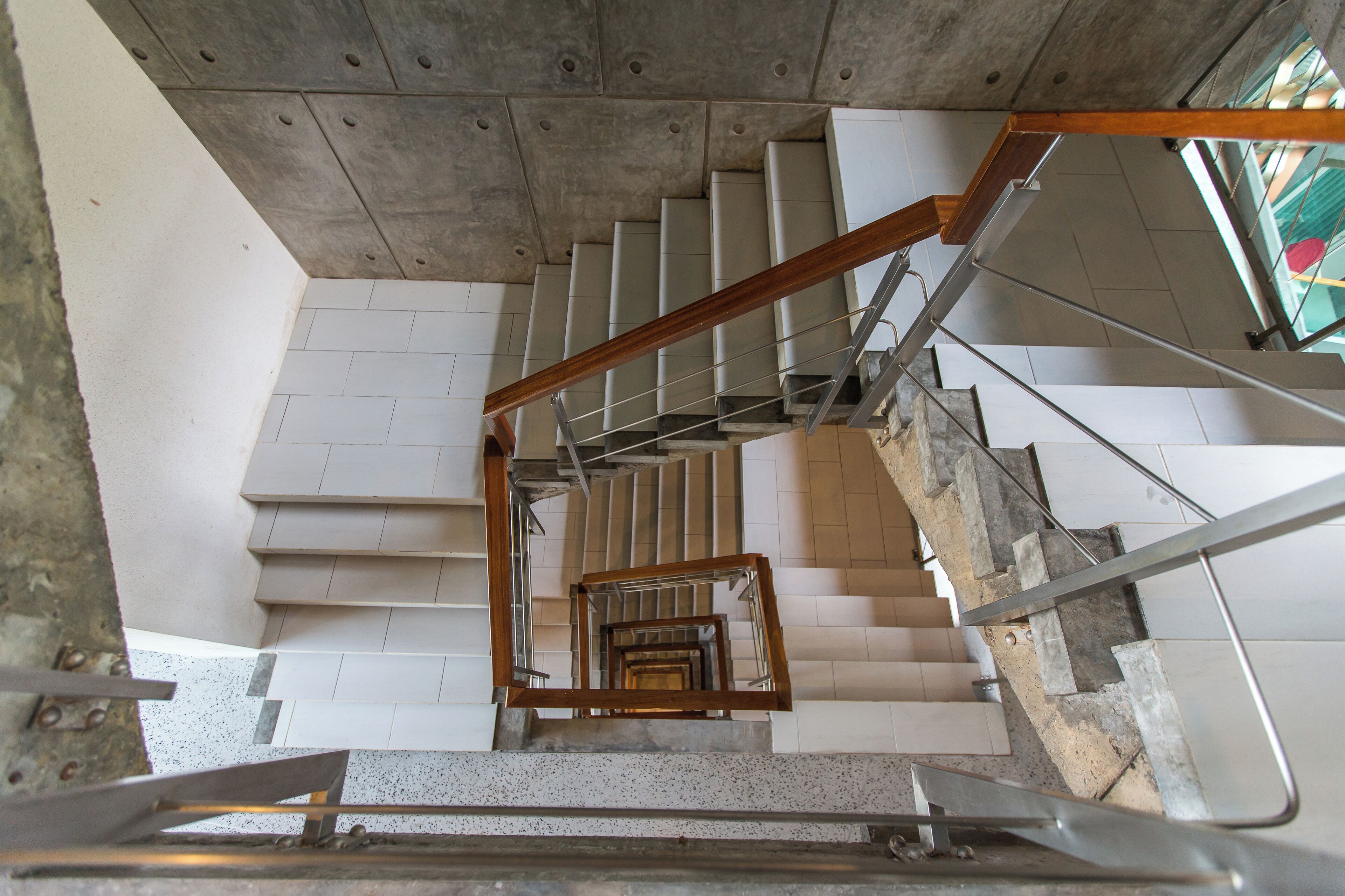 Een meerlaags interieur met een centraal spiraaltrap, betonnen wanden en een metalen leuning.