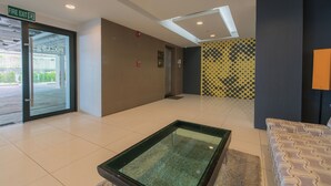 A hotel lobby with a glass table, a fire exit sign, and a patterned wall. - Pixel-modern 1-br Apartment With Pool View in Cape Panwa (Wichit)