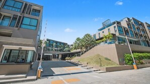 A modern building with multiple floors, large windows, and a staircase leading to the entrance. - Pixel-modern 1-br Apartment With Pool View in Cape Panwa (Wichit)
