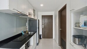 A compact kitchen with a black countertop, stainless steel appliances, and white cabinetry. - Pixel-modern 1-br Apartment With Pool View in Cape Panwa (Wichit)