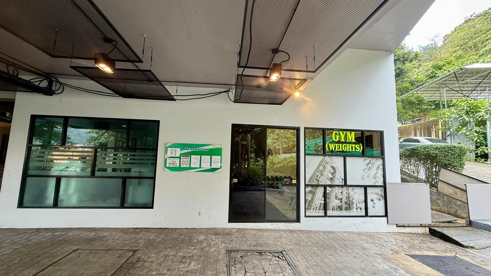 A building with a sign reading 'GYM WEIGHTS' and a bulletin board with information.