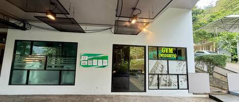 A building with a sign reading 'GYM WEIGHTS' and a bulletin board with information.