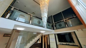 Ein modernes Interieur mit einem prächtigen Kronleuchter, einer Treppe und einem großen Fenster.