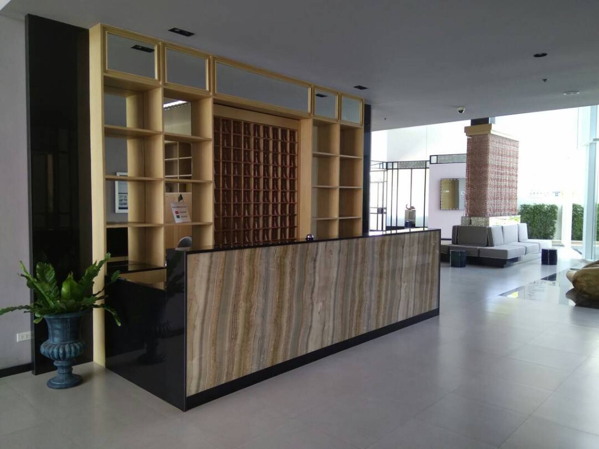 A reception area with a wooden reception desk, glass partitions, and a seating area with a sofa and chairs.