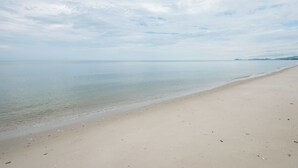 Una amplia playa de arena con aguas tranquilas y una costa lejana.