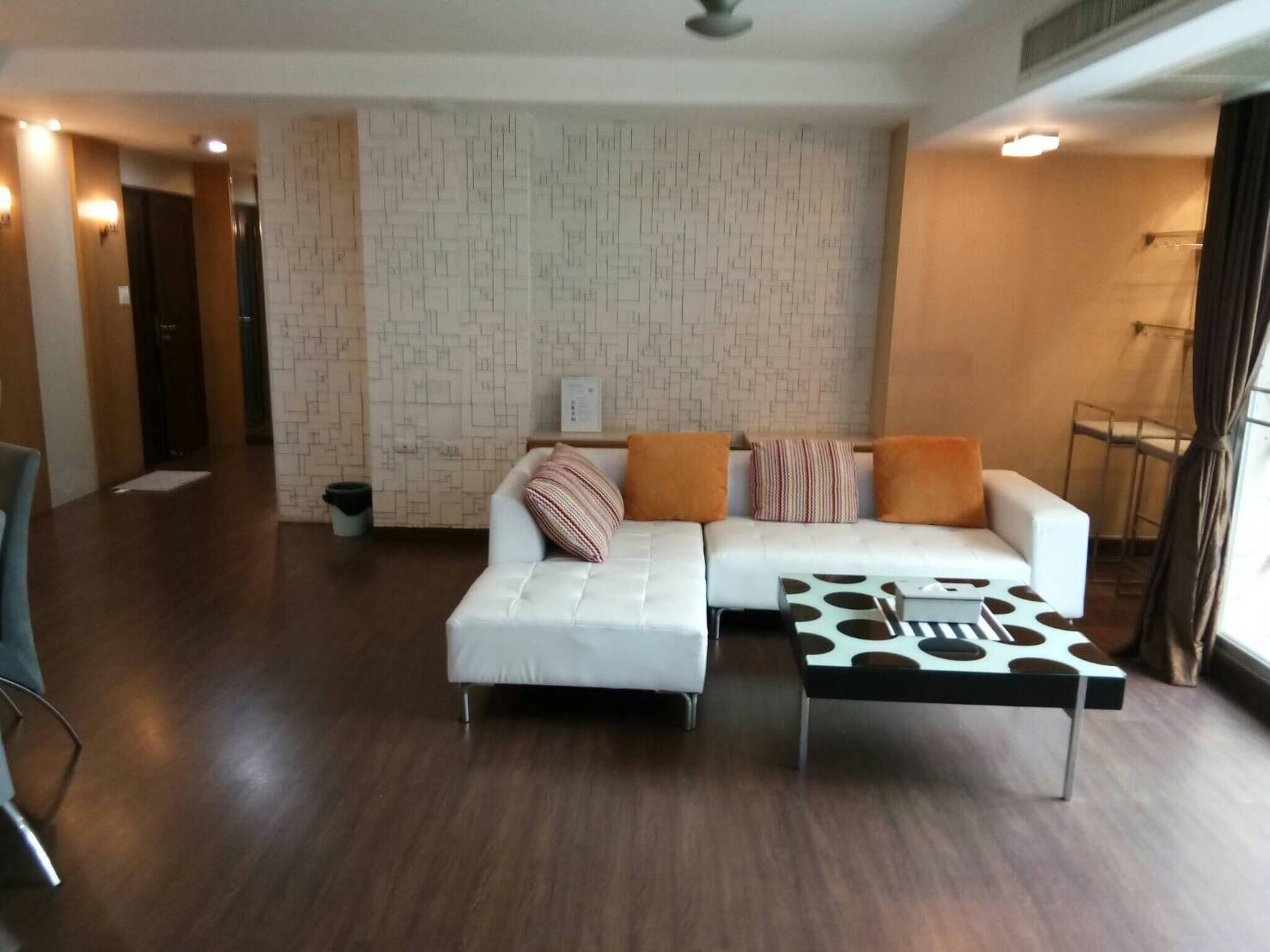 A modern living room with a white sectional sofa, a coffee table with a polka dot design, and a patterned wall.