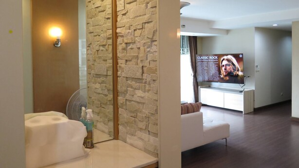 A modern hotel lobby with a stone wall, a reception desk, and a seating area. - 4B - 2 Bedroom Downtown Apartment With Shared Pool (Bangkok)