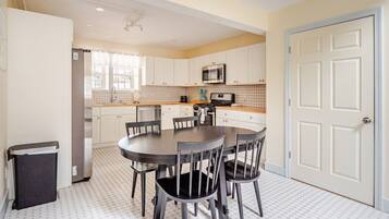 A compact kitchen with white cabinets, a microwave, and a dining table with chairs.