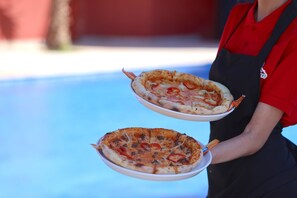 Una persona sosteniendo dos pizzas con ingredientes visibles.