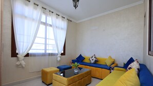 A living room with a sofa set, ottomans, and a coffee table. - Hotel palais d'orient (Tafoughalt)